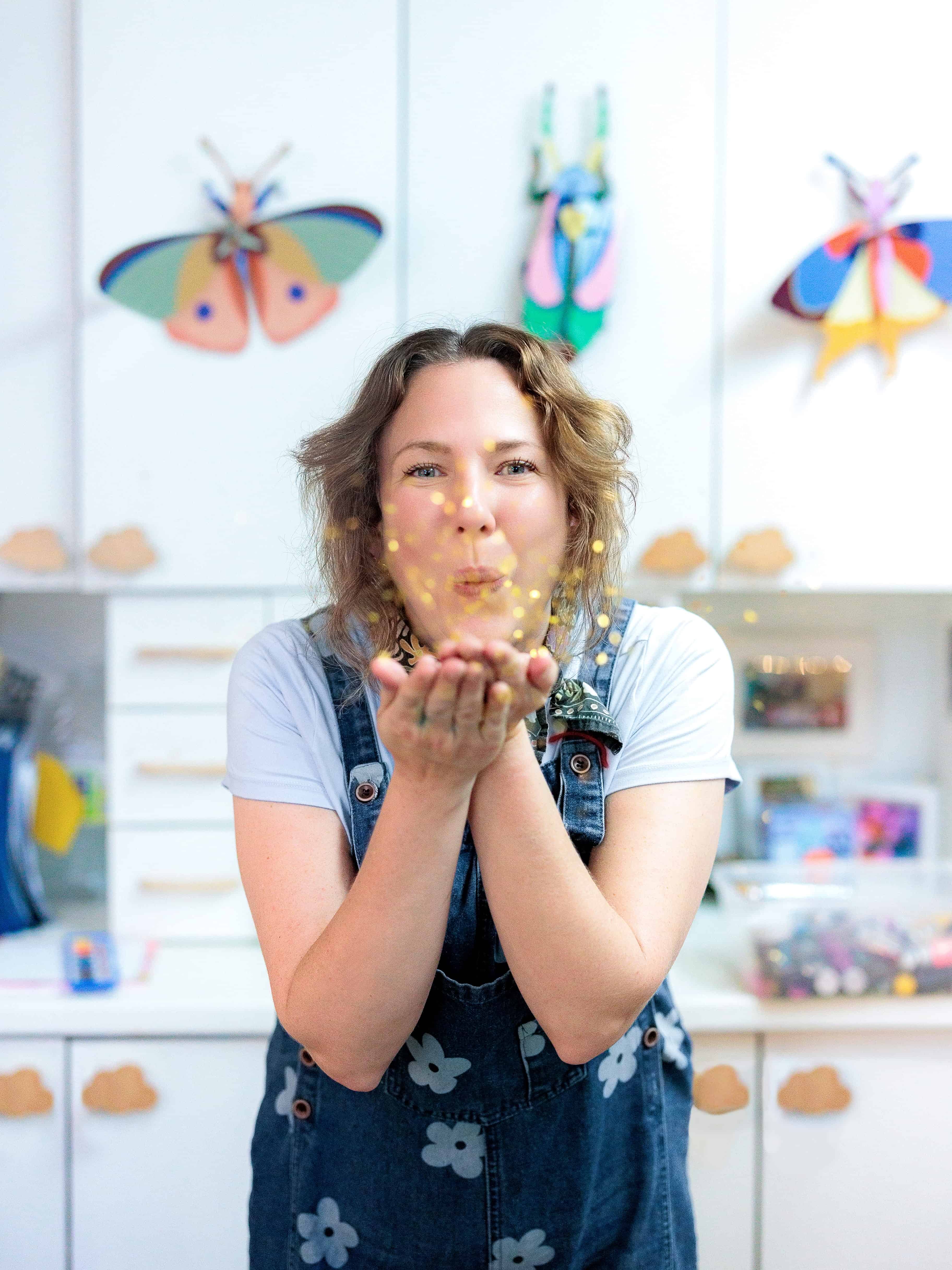Storybook Studio founder blowing glitter in a bright art studio